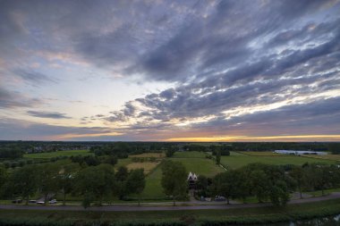 Hollanda 'nın kırsal kesimindeki yemyeşil tarlalara bakan nefes kesici balkon manzarası Amsterdam, Hollanda yakınlarındaki fırtınalı yaz günbatımında