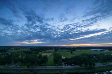 Hollanda 'nın kırsal kesimindeki yemyeşil tarlalara bakan nefes kesici balkon manzarası Amsterdam, Hollanda yakınlarındaki fırtınalı yaz günbatımında