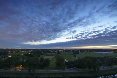 Hollanda 'nın kırsal kesimindeki yemyeşil tarlalara bakan nefes kesici balkon manzarası Amsterdam, Hollanda yakınlarındaki fırtınalı yaz günbatımında