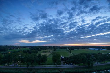 Hollanda 'nın kırsal kesimindeki yemyeşil tarlalara bakan nefes kesici balkon manzarası Amsterdam, Hollanda yakınlarındaki fırtınalı yaz günbatımında