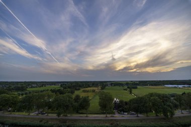 Hollanda 'nın kırsal kesimindeki yemyeşil tarlalara bakan nefes kesici balkon manzarası Amsterdam, Hollanda yakınlarındaki fırtınalı yaz günbatımında
