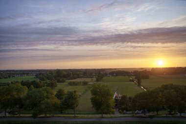 Hollanda 'nın kırsal kesimindeki yemyeşil tarlalara bakan nefes kesici balkon manzarası Amsterdam, Hollanda yakınlarındaki fırtınalı yaz günbatımında