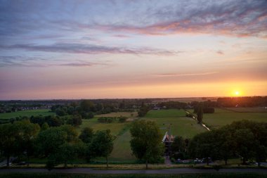 Hollanda 'nın kırsal kesimindeki yemyeşil tarlalara bakan nefes kesici balkon manzarası Amsterdam, Hollanda yakınlarındaki fırtınalı yaz günbatımında