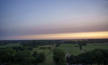 Hollanda 'nın kırsal kesimindeki yemyeşil tarlalara bakan nefes kesici balkon manzarası Amsterdam, Hollanda yakınlarındaki fırtınalı yaz günbatımında