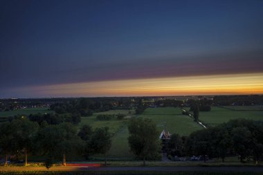 Hollanda 'nın kırsal kesimindeki yemyeşil tarlalara bakan nefes kesici balkon manzarası Amsterdam, Hollanda yakınlarındaki fırtınalı yaz günbatımında