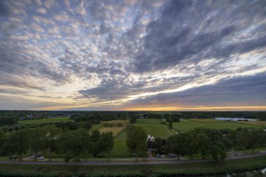 Hollanda 'nın kırsal kesimindeki yemyeşil tarlalara bakan nefes kesici balkon manzarası Amsterdam, Hollanda yakınlarındaki fırtınalı yaz günbatımında