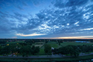 Hollanda 'nın kırsal kesimindeki yemyeşil tarlalara bakan nefes kesici balkon manzarası Amsterdam, Hollanda yakınlarındaki fırtınalı yaz günbatımında