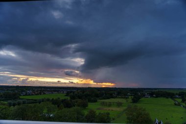 Hollanda 'nın kırsal kesimindeki yemyeşil tarlalara bakan nefes kesici balkon manzarası Amsterdam, Hollanda yakınlarındaki fırtınalı yaz günbatımında