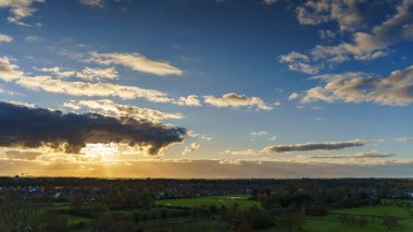 Purmerend 'in şehir siluetine bakan nefes kesici bir balkon manzarası. Hollanda, Amsterdam yakınlarında fırtınalı bir yaz günbatımının dramatik renkleriyle aydınlanıyor.