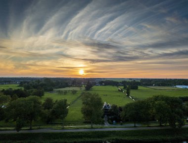 Purmerend 'in şehir siluetine bakan nefes kesici bir balkon manzarası. Hollanda, Amsterdam yakınlarında fırtınalı bir yaz günbatımının dramatik renkleriyle aydınlanıyor.