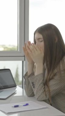 A young woman gracefully practicing various stress relief techniques at her desk while balancing work tasks