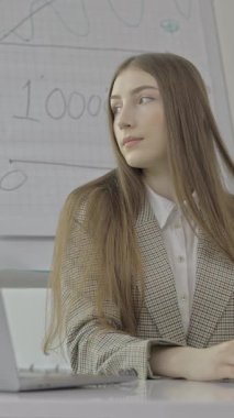A young businesswoman is intently focused on her laptop screen while analyzing various data charts in a modern office