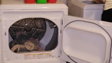 A clothes dryer that is filled with freshly laundered laundry, showcasing a typical scene of a laundry room