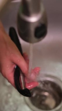 Bir insan mutfak lavabosunda taze bir patatesi yıkıyor ve soyuyor. Yemek yapmaya hazırlanıyor.