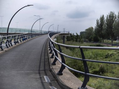 Curved bridge walkway with metal railings showing pathway perspective and structural design