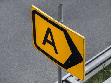 Yıpranmış sarı yol işaretinin ayrıntılı görüntüsü, montaj donanımlı A harfini gösteriyor.