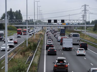 Dense highway traffic with multiple vehicles including trucks under overpass bridge