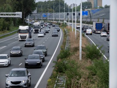 Multiple vehicles including trucks and cars on highway with urban infrastructure visible