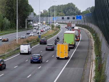 Highway traffic featuring trucks with colorful cargo containers in mixed vehicle flow