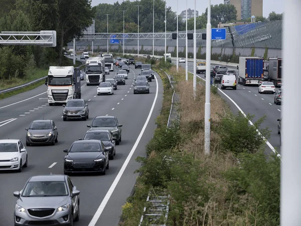 Multiple vehicles including trucks and cars on highway with urban infrastructure visible