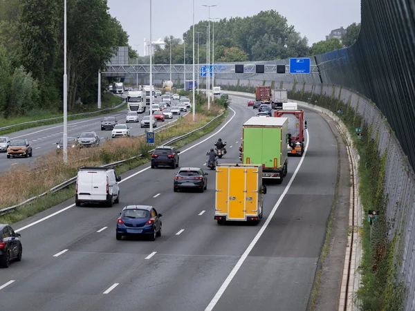 Highway traffic featuring trucks with colorful cargo containers in mixed vehicle flow