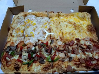 Lezzetli dikdörtgen pizza çeşitleri karton bir kutuda çeşitli malzemeler. Lezzetli bir yemek ya da aile ve arkadaşlarla atıştırmaya hazır..