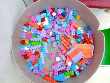 Çok renkli plastik yapı taşlarıyla dolu bir konteynır yaratıcı oyun ve eğitim gelişimi için çeşitli şekil ve boyutlar sunar. Bu resim çocukluk temaları için mükemmeldir..