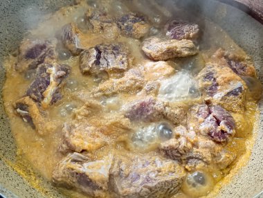 Et parçaları altın bir sosta kaynıyor, tavada nazikçe kaynıyor yemek blogları ve yemek siteleri için mükemmel..