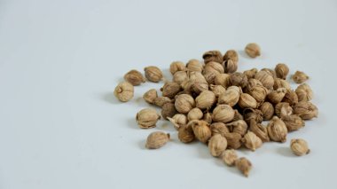 Beyaz bir yüzey üzerinde küçük kahverengi baharat kapsülleri bir araya toplanmış basit bir natürmort görüntüsü oluşturur, tarifler veya çizimler için uygundur..