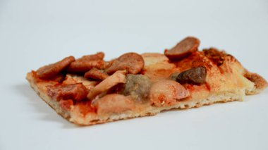 Sade beyaz bir yüzeye sergilenen sosis ve mantarla kaplı tek bir pizza diliminin yakın çekimi. Yemek fotoğrafçılığı ve menü tasarım projeleri için harika..