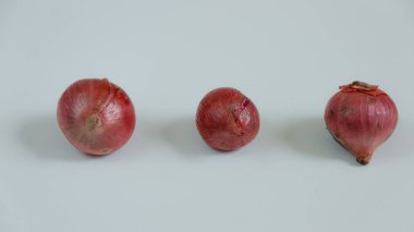 Üç kırmızı soğan, çeşitli tariflerde kullanılmak üzere sade ve hafif bir yüzeye yerleştirilir. Yemek pişirmek için birebirdir..