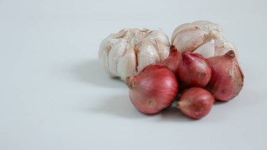 Bir grup sarımsak soğanı ve soğan sade beyaz bir zemin üzerinde oturur. Yemek pişirmek ve yemek malzemesi kavramları için mükemmeldir..