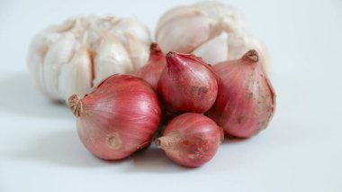 Beyaz bir yüzey üzerinde taze soğan ve sarımsak soğanları sergilenen durgun bir yaşam. Mutfak ya da yemekle ilgili içerik için mükemmel..