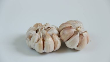 Karanfilli iki sarımsak soğanı sade beyaz bir zemin üzerinde gösteriliyor. Mutfak içeriği ve sağlıklı beslenme kaynakları için mükemmel..