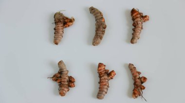 Açık renkli bir yüzey üzerinde ham zerdeçal kökleri sergilenir ve doğal bir doku sunar. Yemek pişirmek ve sağlıklı olmak için mükemmeldir..