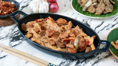 Siyah bir tabakta servis edilen sosisli ve sebzeli tuzlu kızartma yemek blogları ve yemek sunumları için mükemmel bir davet sunumu yaratır..