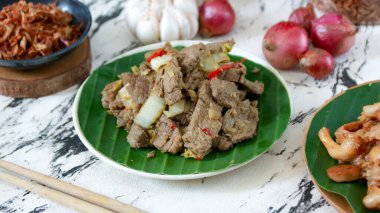Dilimlenmiş sebzeli leziz kızarmış biftek soğan ve sarımsağın yanında, yaprak kaplı bir tabakta oturur. Akşam veya öğle yemeğinde afiyet olsun..