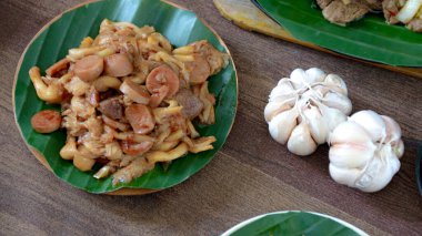 Yemek blogları ve mutfak içeriği için mükemmel ahşap bir masada sarımsaklı sosis ve kızarmış mantarla servis edilen bir tabağı kapat..