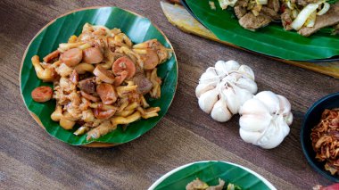 Birkaç tabak kızarmış sosis ve istiridye mantarı ahşap bir masada dinleniyor, sarımsak karanfili ile servis ediliyor yemek kitapları için yemek fotoğrafçılığı mükemmeldir..
