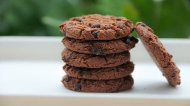 Bulanık yeşil bir zemin üzerinde sunulan taze pişmiş çikolatalı kurabiye yığını, pişirme ve atıştırma kavramları için ideal..