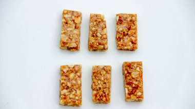 Beyaz arka planda altı tane fıstık ezmeli çikolata, çıtır çıtır dokularını ve altın renklerini sergiliyorlar. Bu ev yapımı atıştırmalıkları veya tatlı ikramları göstermek için idealdir..