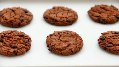 Birkaç çikolata parçalı kurabiye sade beyaz bir yüzeye yerleştirilir ve tatlı bir ikram veya atıştırmalık olarak sunulmaya hazırdır. Gıda içeriği veya pişirme kavramları için mükemmel.