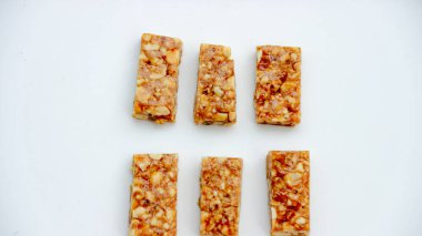 Sağlıklı atıştırmalıkları veya ev yapımı ikramları göstermek için mükemmel olan bu tepeden çekimde, temiz beyaz bir yüzeyde altı tane fındık çubuğu düzgün bir şekilde düzenlenmiştir..