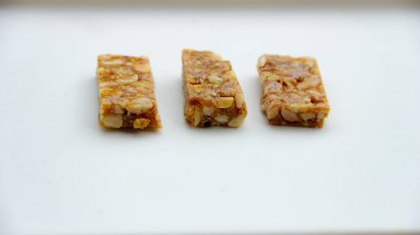 Üç parça fıstık ezmesi, desen ve malzemelerini sergilemek için sade beyaz bir yüzey üzerinde dizilir. Bu, ev yapımı şekerlemeler ve atıştırmalıklar için idealdir..