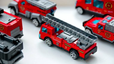 Minyatür itfaiye kamyonlarının parlak, beyaz bir yüzeye yerleştirilmiş bir koleksiyonu çocukluk kavramları ve araç koleksiyonları için uygun bir oyun sahnesi oluşturuyor..