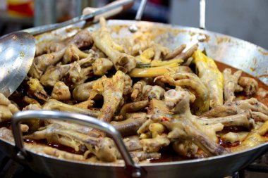 Tavuk ayağı ve diğer malzemelerle dolu büyük metal tava yemek blogu veya yemek tarifi içeriği için mükemmel bir sosta kaynıyor..