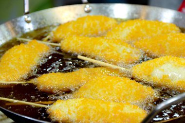 Tahta çubuklarda çıtır çıtır gıdalar, gümüş metal bir tavada kızgın yağda kızartılıyor, yemek içeriği ve yemek pişirme gösterileri için mükemmel..