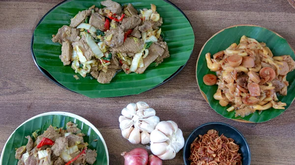 Çeşitli tabaklar sebzeli kızarmış et servis edilmeye hazır ahşap bir masaya konur. Yemek içeriği ve yemek hazırlama fikirleri için harikadır..