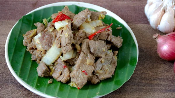 Sarımsak ve soğan ile birlikte dekoratif tabakta servis edilen soğanlı kızarmış sığır eti yakın plan Asya mutfağını veya yemek fotoğrafçılığını resmetmek için birebirdir..