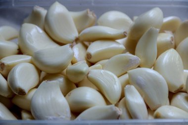 Taze soyulmuş sarımsak karanfilleri toplanmış, doğal şekillerini ve dokularını sergiliyorlar, aşçılık hazırlığı ve yemekle ilgili içerik için mükemmel..